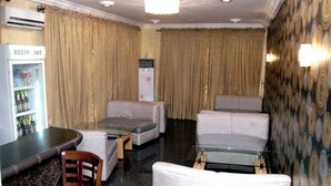 Une chambre d’hôtel comprenant un coin bar, un réfrigérateur rempli de boissons et un espace salon avec deux canapés et un fauteuil.
