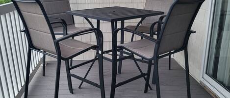 Un patio cubierto con una mesa y cuatro sillas, un muro decorativo y una puerta de cristal.