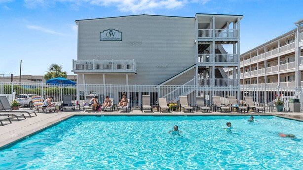 Una piscina con sillas de descanso y un edificio con el letrero 'W Condominiums'.