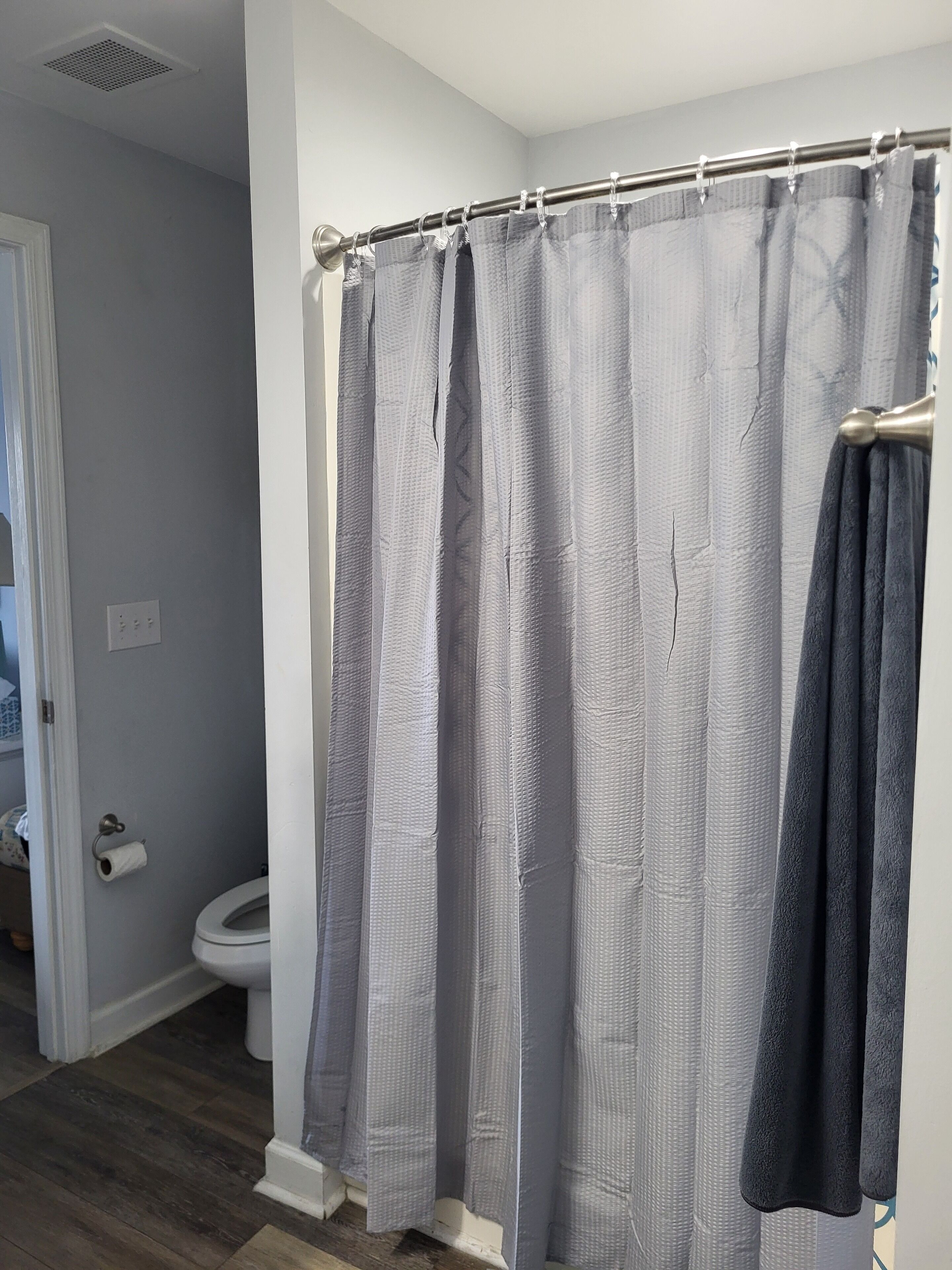 A bathroom with a shower curtain, toilet, and a towel rack.