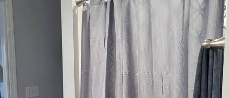 A bathroom with a shower curtain, toilet, and a towel rack.