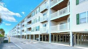 Un hotel de varios pisos con balcones, estacionamiento y cielo despejado.