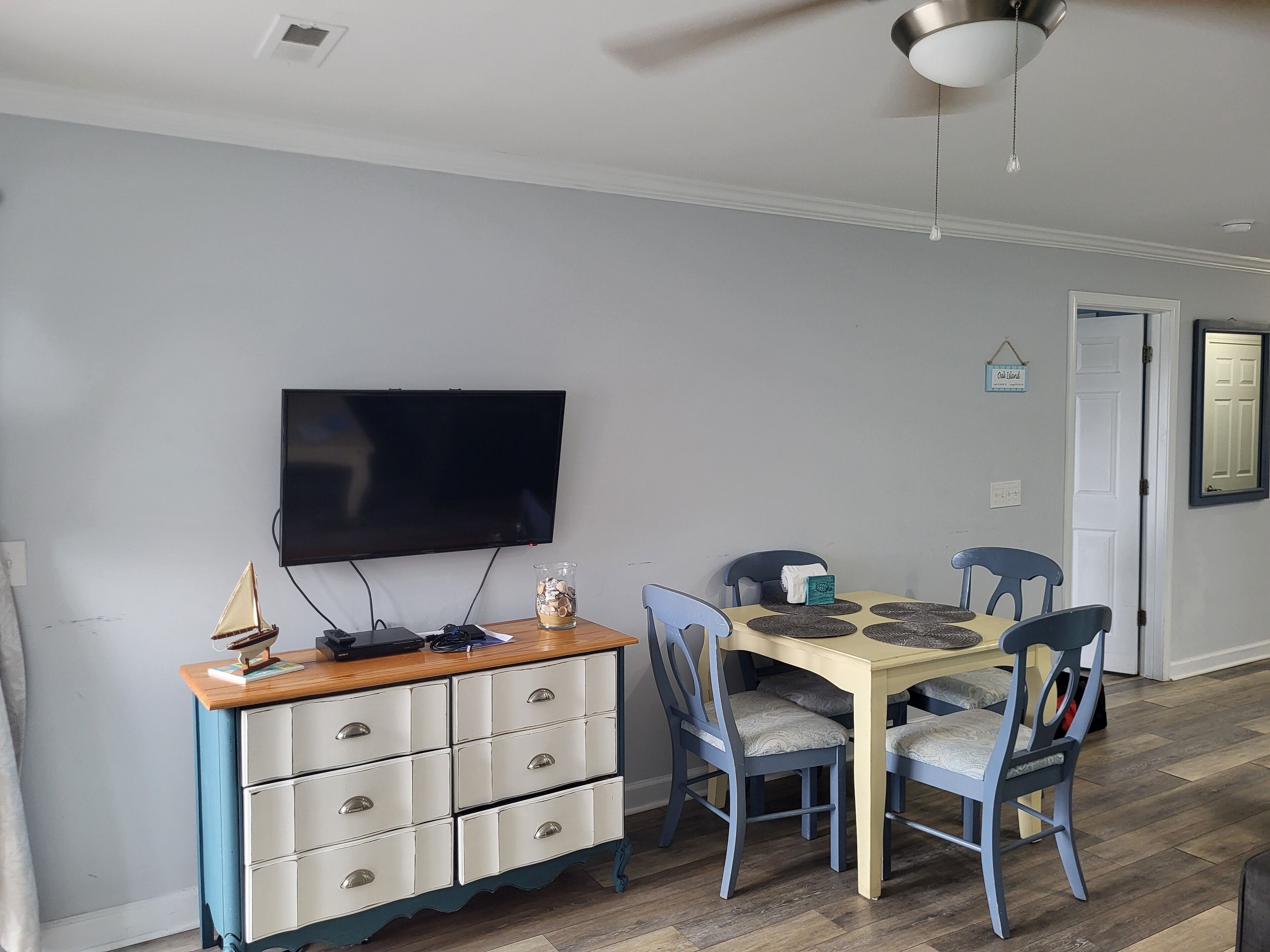 A dining area with a table, chairs, a television, and a cabinet.