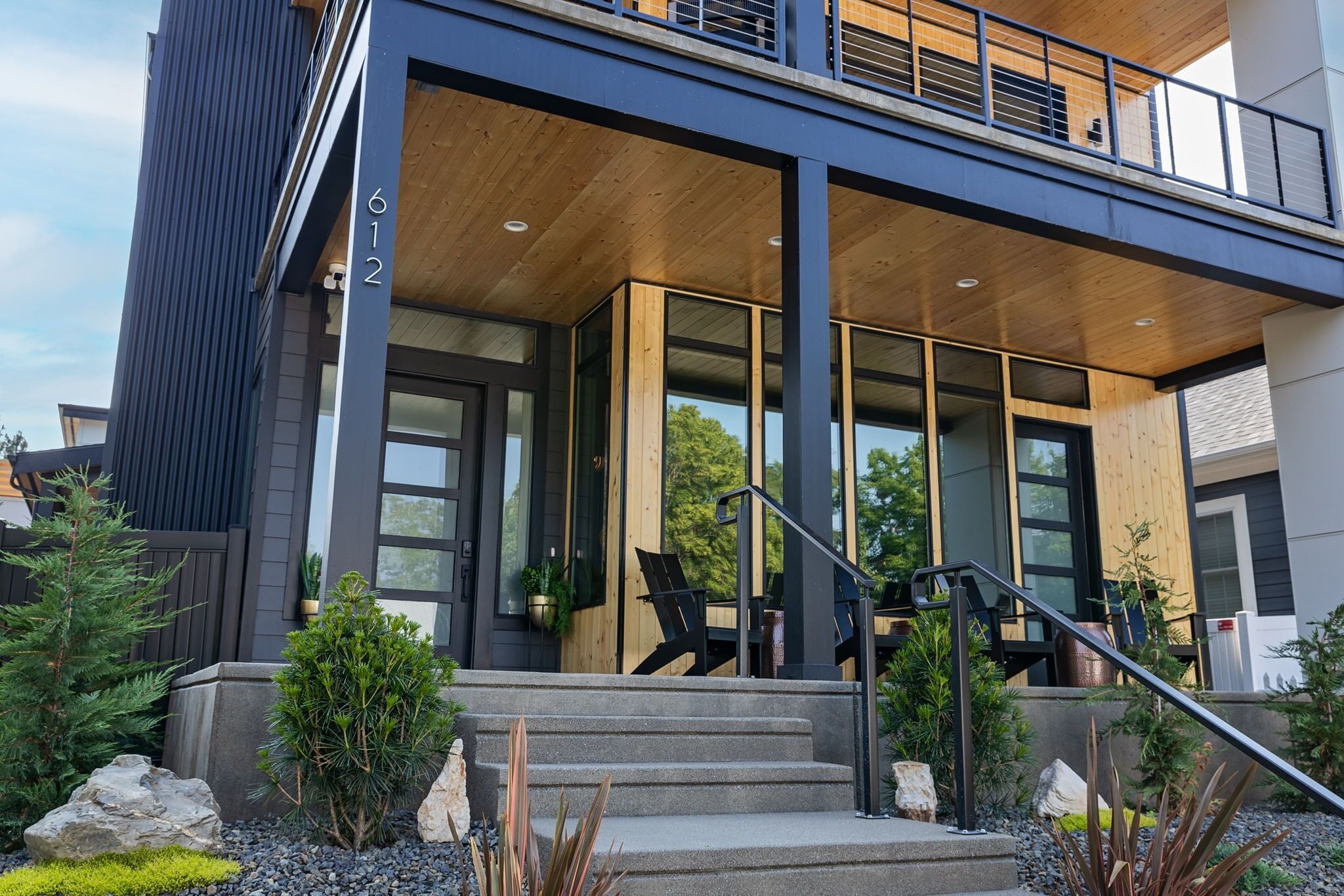 A modern two-story building with a wooden deck and a staircase leading to the entrance.