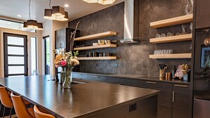 Una cocina moderna con una isla grande, estantes empotrados y un salpicadero de azulejos hexagonales.