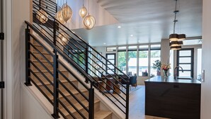 Un interior moderno con escaleras, piso de madera e iluminación colgante.
