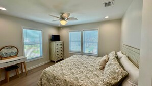 A bedroom with a bed, a desk, a chair, a dresser, and a ceiling fan. - Docked at Dakota Sunset - Mid Island Pool Home (Fort Myers Beach)
