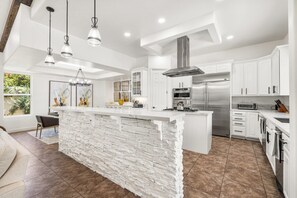 Une cuisine moderne avec des meubles blancs, un îlot central et des appareils électroménagers en acier inoxydable.