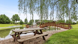 Een houten picknicktafel bij een vijver, met een kiosk en een houten brug.