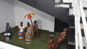 Uma representação de uma cena tradicional com figuras em trajes coloridos, uma escada e um lance de degraus.