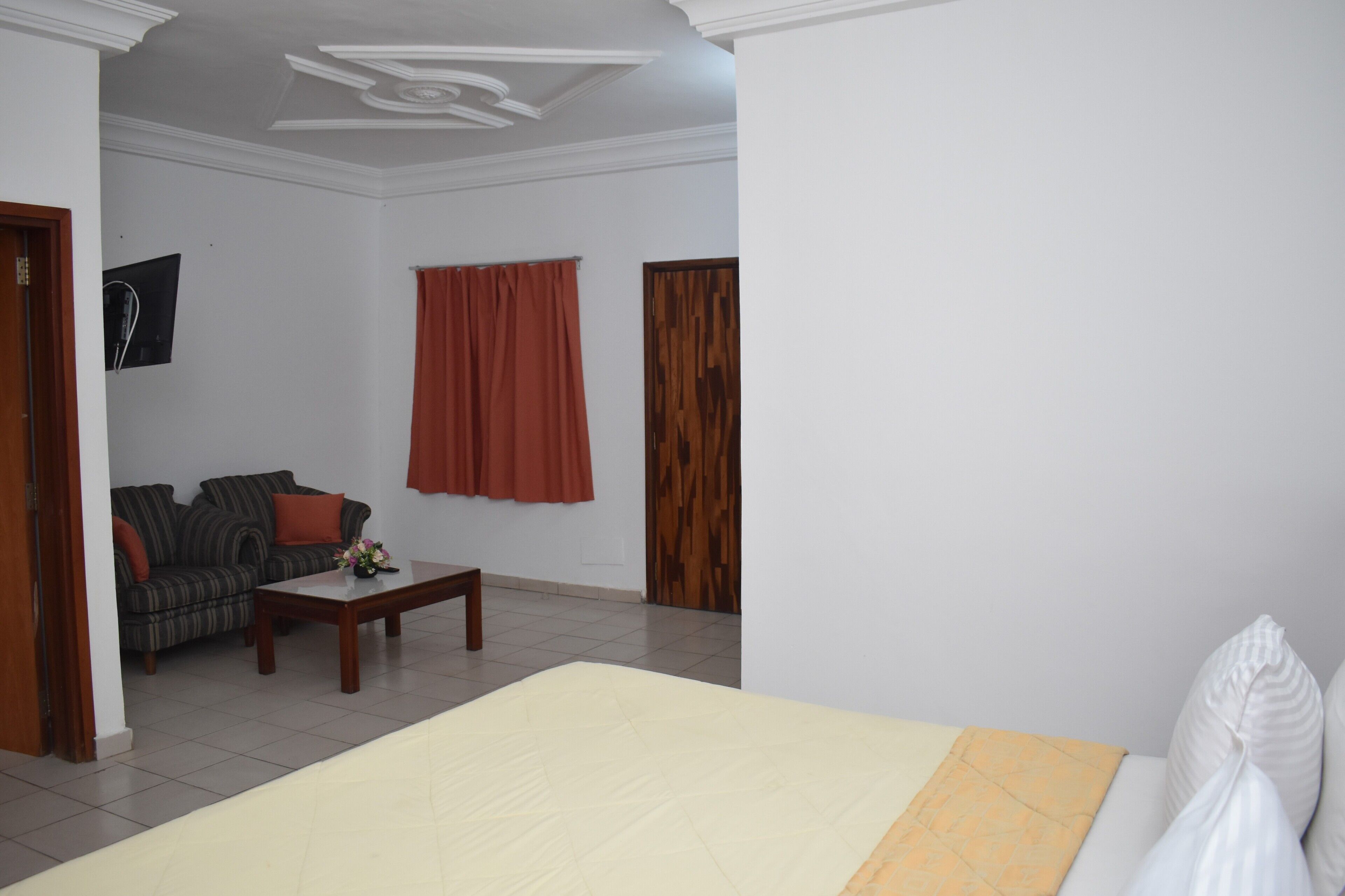 Una habitación con una cama, un sofá, una mesita de centro y una puerta de madera.