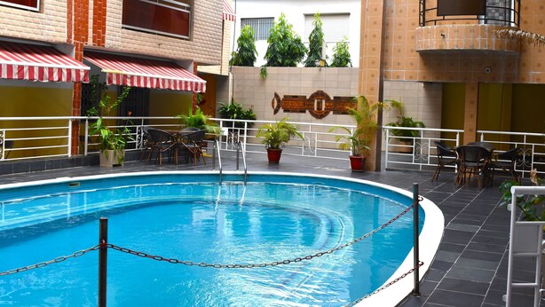 Piscina interna com barreira de corrente, cercada por plantas em vasos e móveis de exterior.