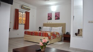 Quarto com cama, mesa de cabeceira, espelho e um vaso com flores.