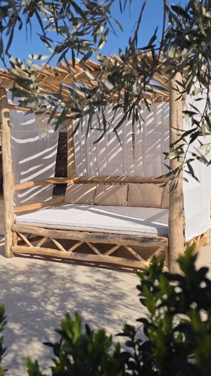 A wooden bench with a cushion, a hanging chandelier, and a pergola structure. - Charming stone house near Sommieres, 35 mn from the beach Swimming pool and Spa (Boissières)