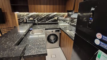 Eine moderne Küche mit integriertem Waschtrockner, Edelstahlgeräten und Holzschränken.