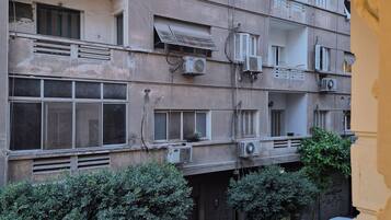A multi-story building with balconies, air conditioning units, and a hanging light fixture.
