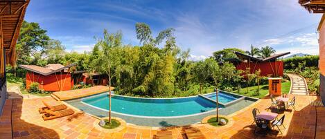 A pool area with a curved design, surrounded by lounge chairs and a small table with chairs.