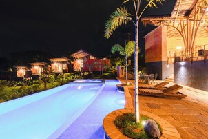 A swimming pool with a tiled deck, surrounded by lounge chairs and a small garden area.
