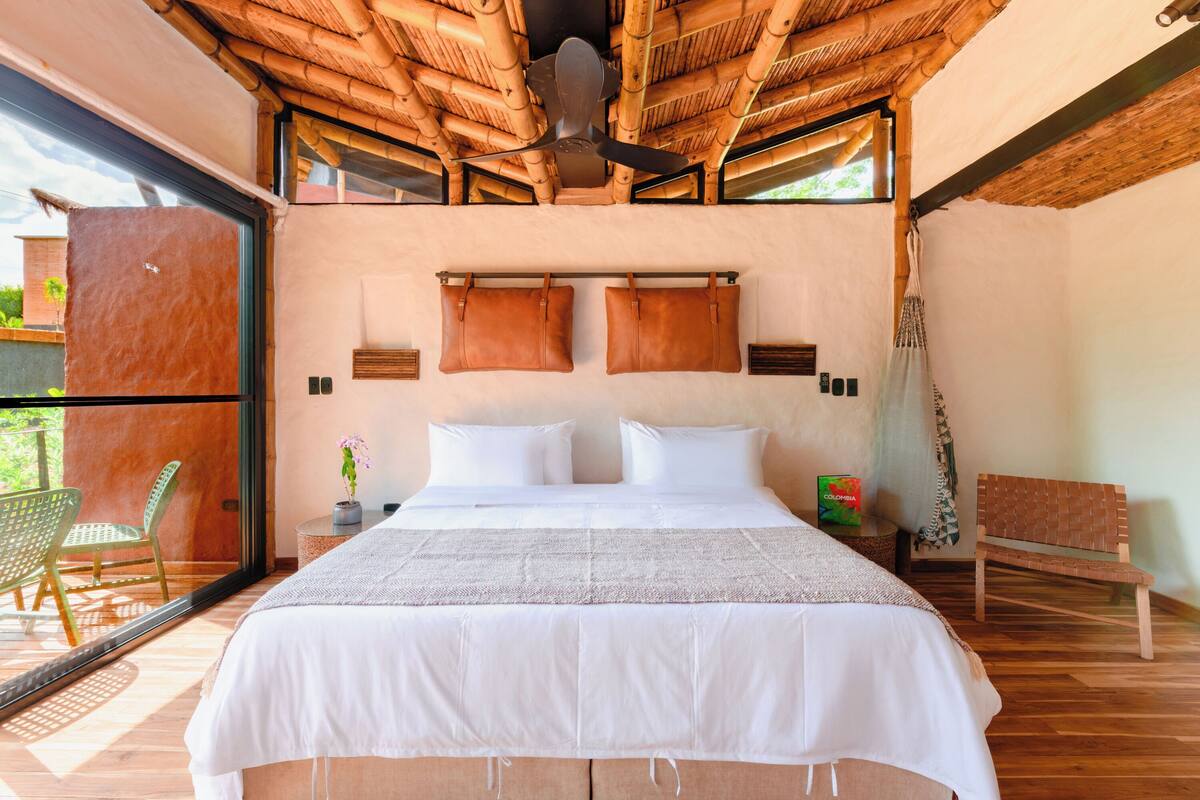 Une chambre dotée d’un grand lit, d’un ventilateur de plafond et offrant une vue sur l’extérieur.