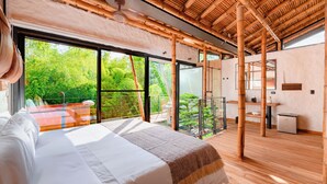 Ein Schlafzimmer mit einem großen Bett, einem Balkon mit Glastür und Blick auf Grünflächen.