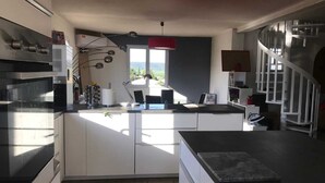 A modern kitchen with a central island, built-in appliances, and a view of the outdoors. - Air-conditioned villa with large swimming pool (Le Pouget)