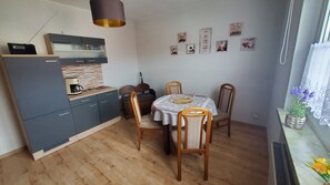 A compact kitchen with a coffee maker, a dining table with chairs, and a small window with a plant.