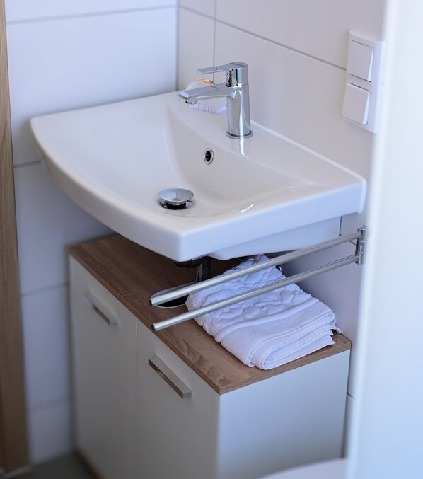 A bathroom with a white sink, a towel rack, and a wooden cabinet.
