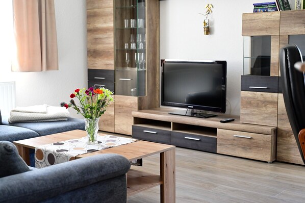 A modern living room with a sofa, a coffee table, a TV, and a cabinet.