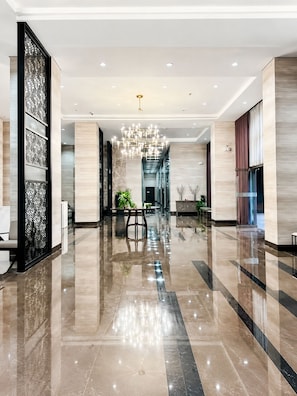 A spacious lobby with a reflective floor, a central chandelier, and a seating area with tables and chairs. - Manila Bay View - 1BR with balcony (Pasay)