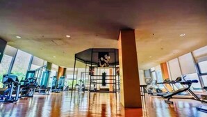 A gym with exercise equipment, large windows, and a central pillar. - Manila Bay View - 1BR with balcony (Pasay)