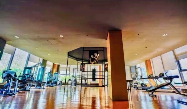 A gym with exercise equipment, large windows, and a central pillar. - Manila Bay View - 1BR with balcony (Pasay)