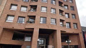A multi-story building with a brick facade, multiple balconies with potted plants, and a ground-level entrance with a sign. - Hotel San Felipe 74 (Bogota)