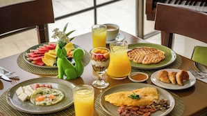 A breakfast table with plates of food, a pitcher of orange juice, and a bowl of soup. - Hotel San Felipe 74 (Bogota)