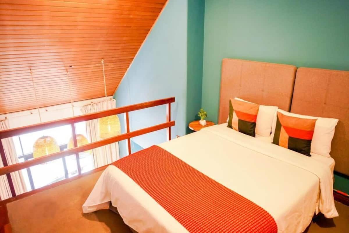 A bedroom with a bed, a nightstand, a window with curtains, and a balcony.