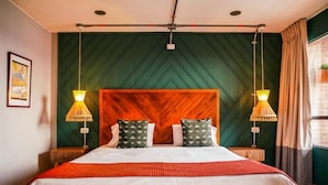 A hotel room with a large bed, two bedside lamps, a wooden headboard, and a green patterned wall. - Hotel San Felipe 74 (Bogota)
