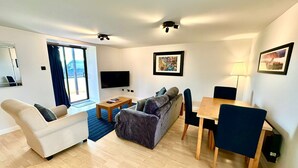 Una sala de estar moderna con un sofá, una mesa de centro, un televisor y un comedor con sillas y una mesa.