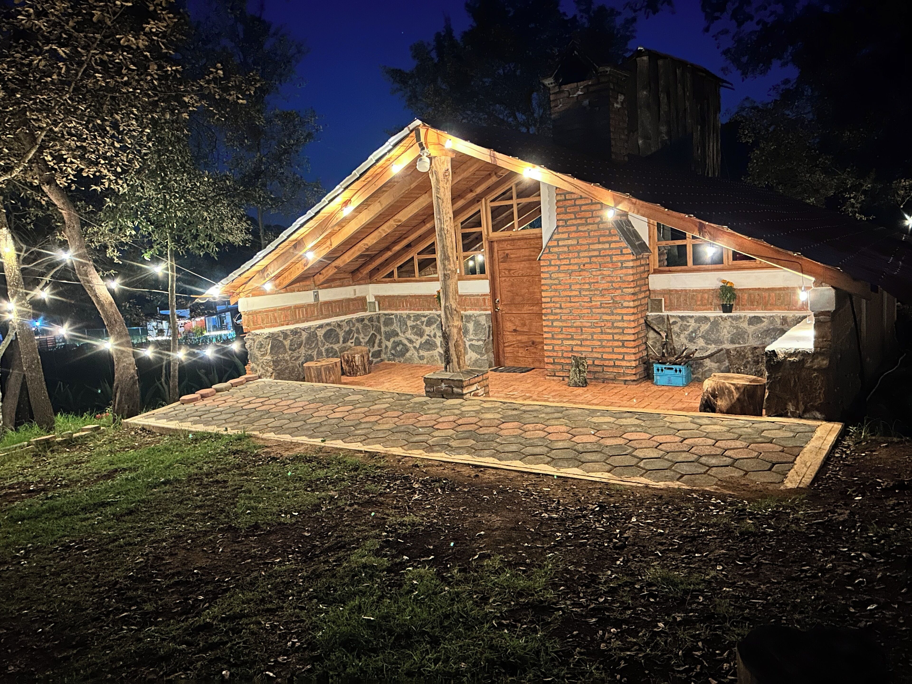 A rustic cabin with a stone foundation, wooden beams, and a sloped roof.