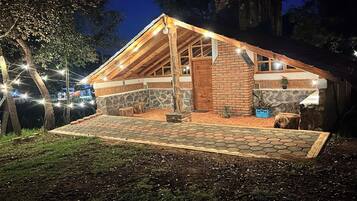 A rustic cabin with a stone foundation, wooden beams, and a sloped roof.
