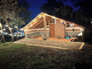 A rustic cabin with a stone foundation, wooden beams, and a sloped roof.