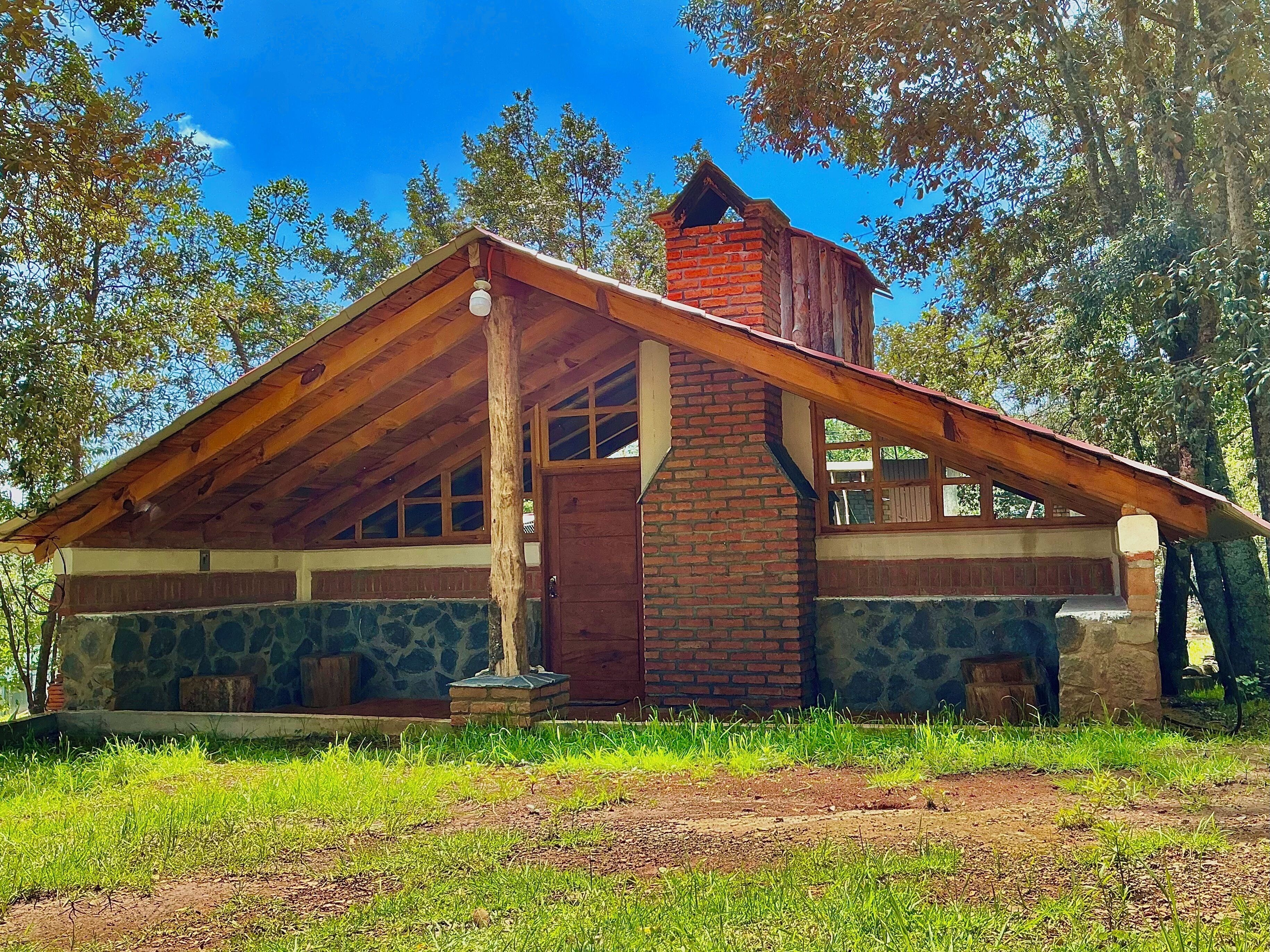 Une cabane rustique avec des fondations en pierre, des poutres en bois et une cheminée en briques.