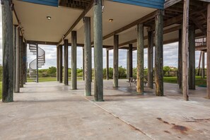 A covered outdoor area with concrete flooring, wooden pillars, and a spiral staircase. - Sandy Hook by Ryson Vacation Rentals (Galveston)