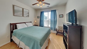 A bedroom with a bed, a desk, a television, and a ceiling fan. - Sandy Hook by Ryson Vacation Rentals (Galveston)