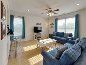 A living room with a sofa, a coffee table, a TV, and a ceiling fan.