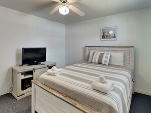 A bedroom with a bed, a television on a stand, a ceiling fan, and a framed picture on the wall. - Casa de Reyes by Ryson Vacation Rentals (Galveston)