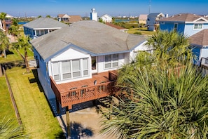 A two-story house with a balcony, surrounded by palm trees and a clear sky. - Casa de Reyes by Ryson Vacation Rentals (Galveston)