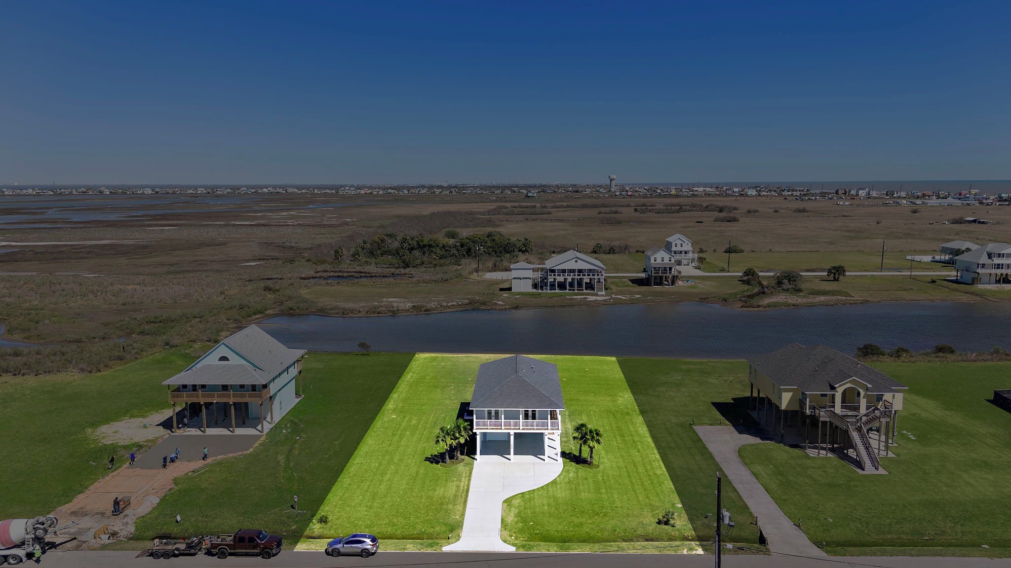 An aerial view of a residential area with a large house featuring a spacious lawn and a driveway leading to a gated entrance.