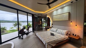 Un dormitorio moderno con una cama grande, equipo de ejercicio y vista al mar.