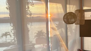 Una sala de estar moderna con ventanas amplias, un sofá, una mesa de centro y una lámpara colgante.