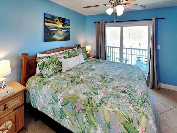 A bedroom with a bed, a nightstand, a painting, and a balcony with curtains.