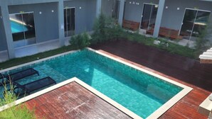 Une piscine extérieure moderne avec une terrasse en bois et des chaises longues.